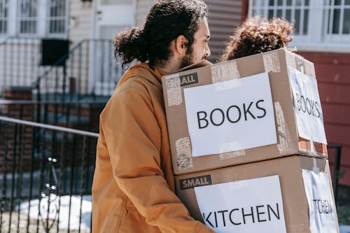 Man Carrying Boxes Of Books And Kitchen Wares