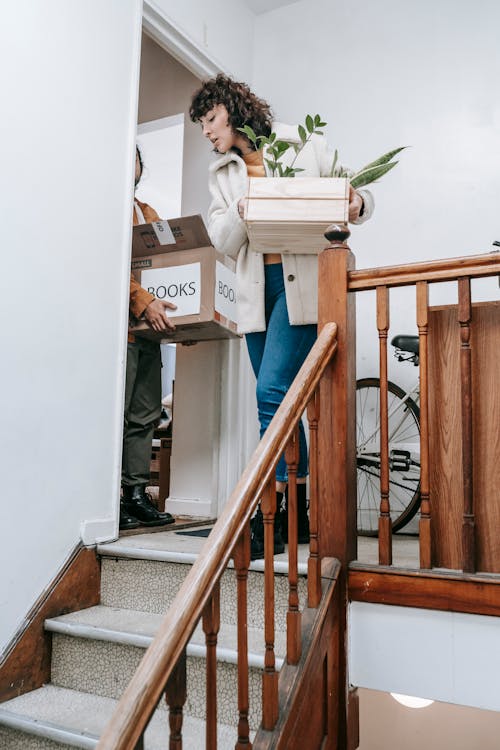 Woman Standing Near The Stairs With A Box Of Plants