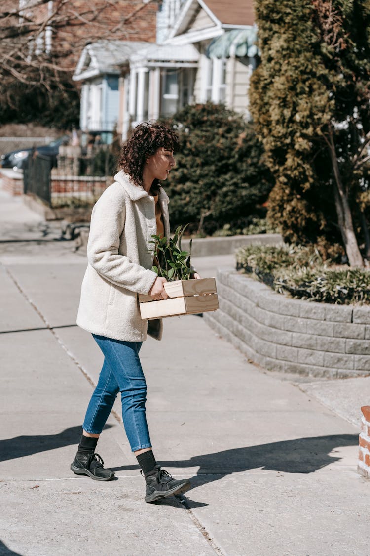 Woman Carrying A Wooden Box With Plants