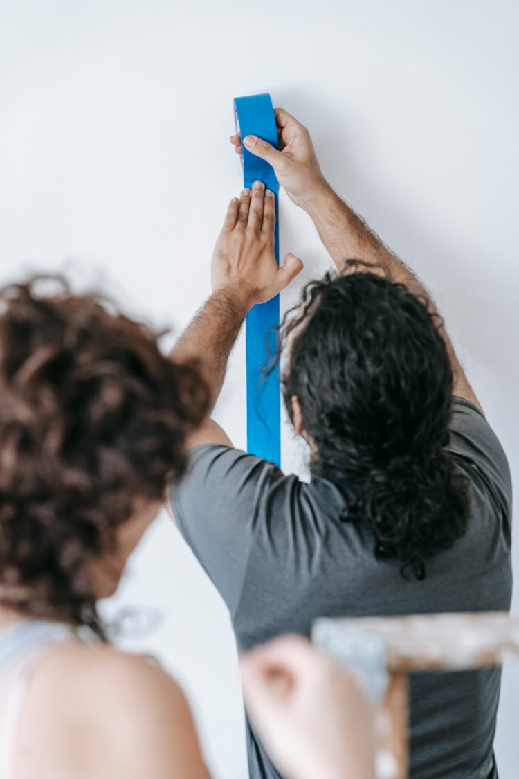 Man In Gray Shirt Putting Tape On Wall