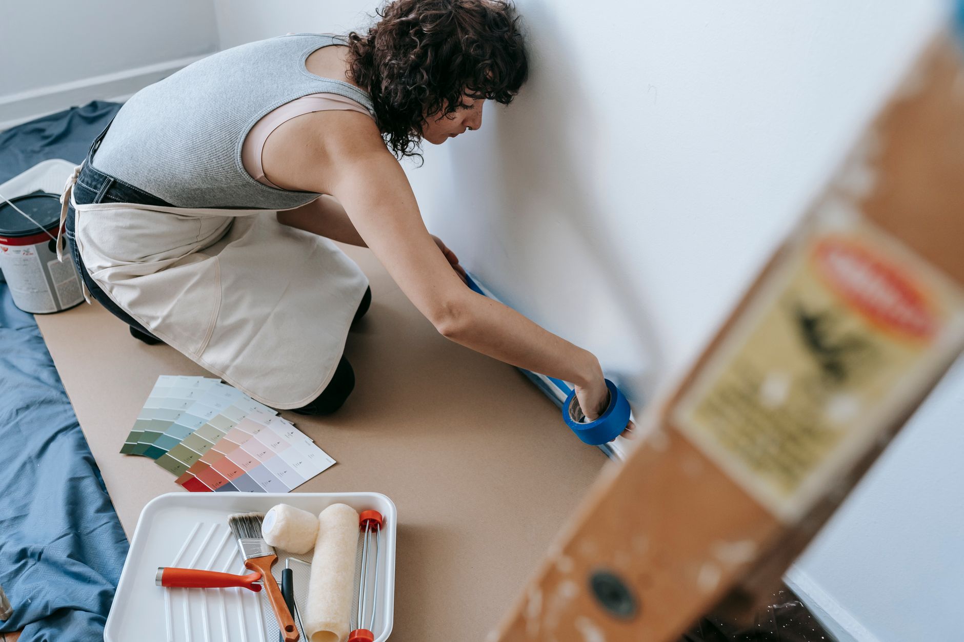 Female using blue tape for home painting project in a modern apartment.
