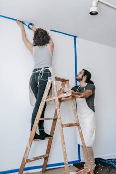 A couple working together on a home renovation project using blue painter's tape indoors.