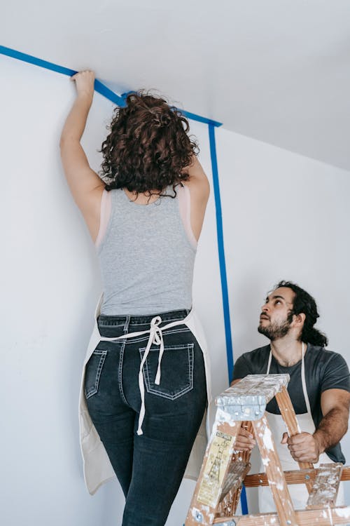 Woman Putting Adhesive Tape On Wall