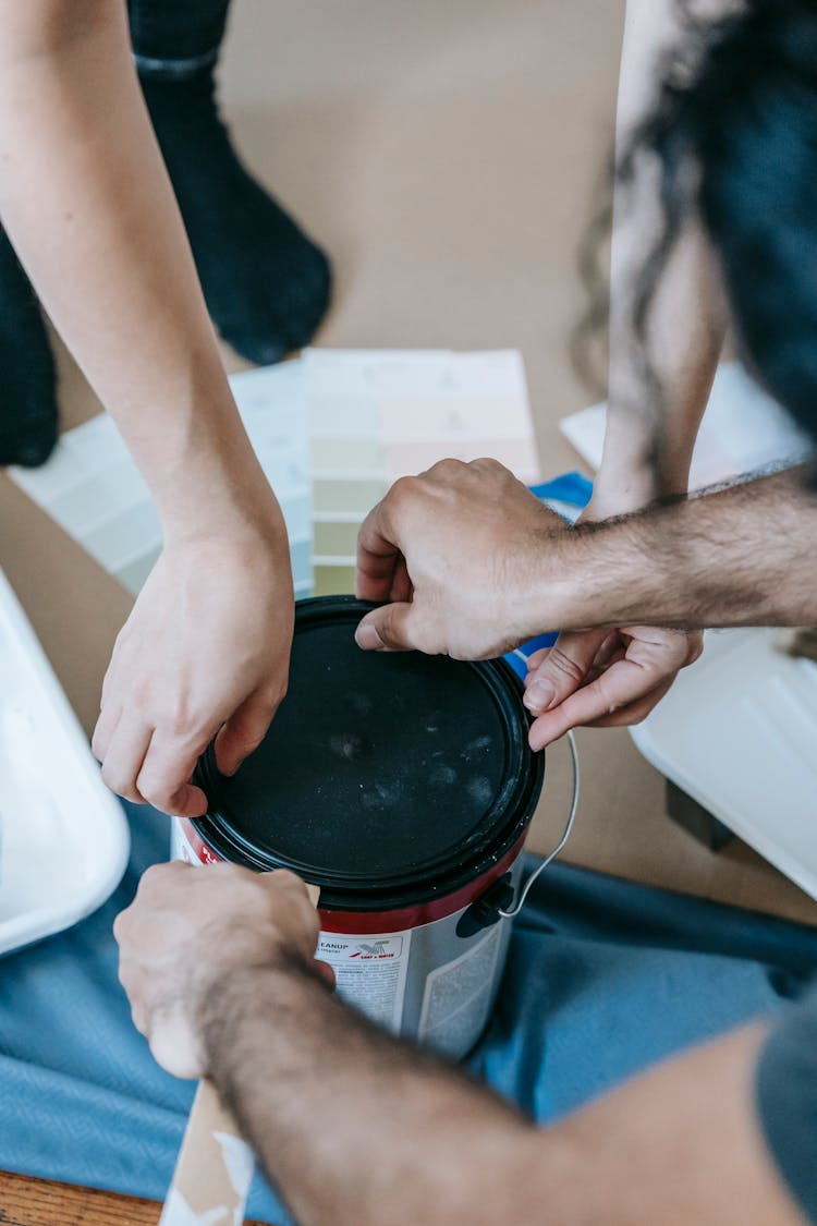 Two People Opening A Can Of Paint