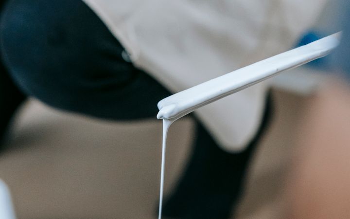 Close-up of a woman mixing white paint, ready to apply in a home renovation project.