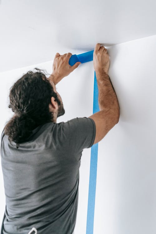 Man Putting Adhesive Tape On Wall
