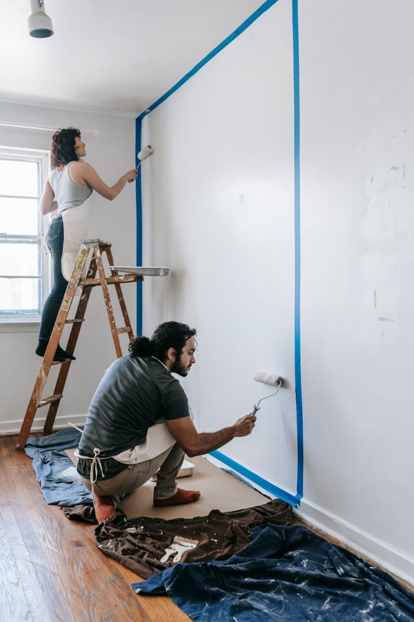 Casal pintando a parede de casa