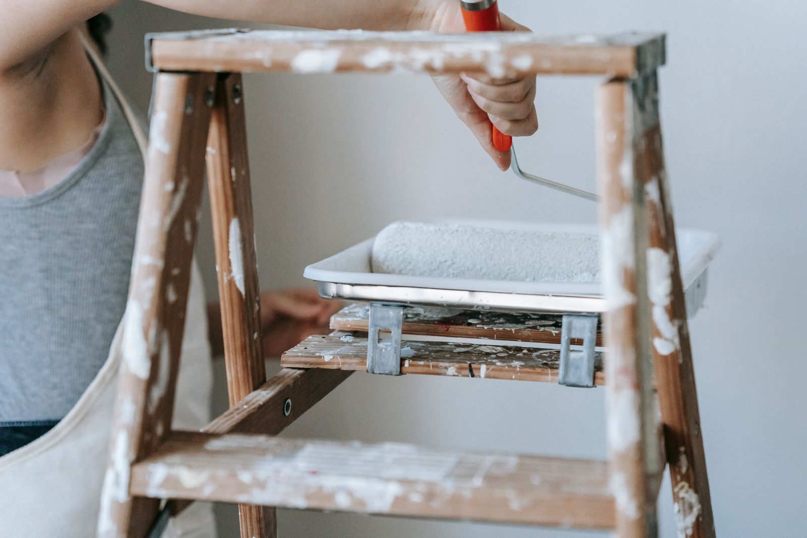 Decorator working from a ladder with a paint roller during an interior repaint