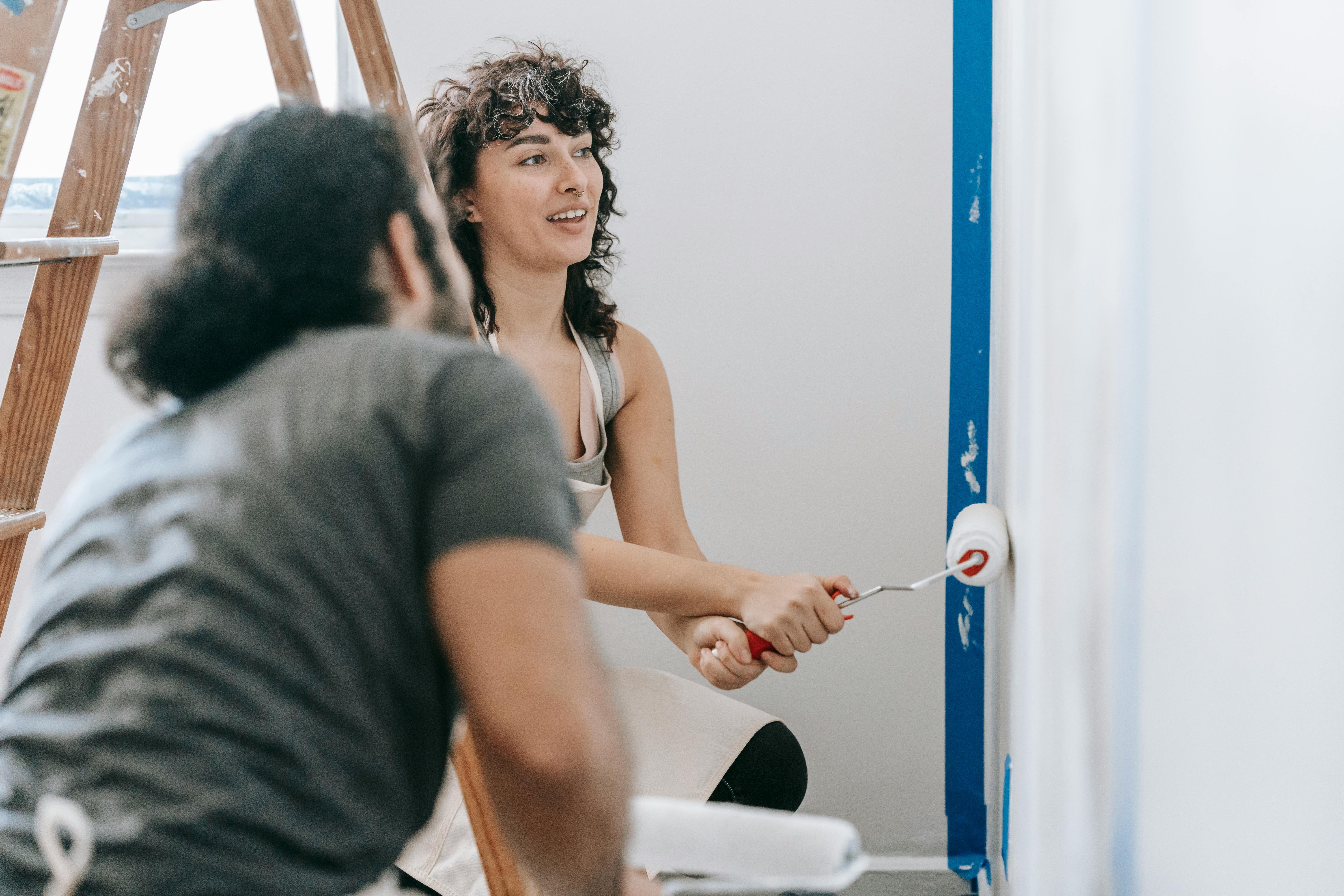 A happy couple painting a wall together during a home renovation project.