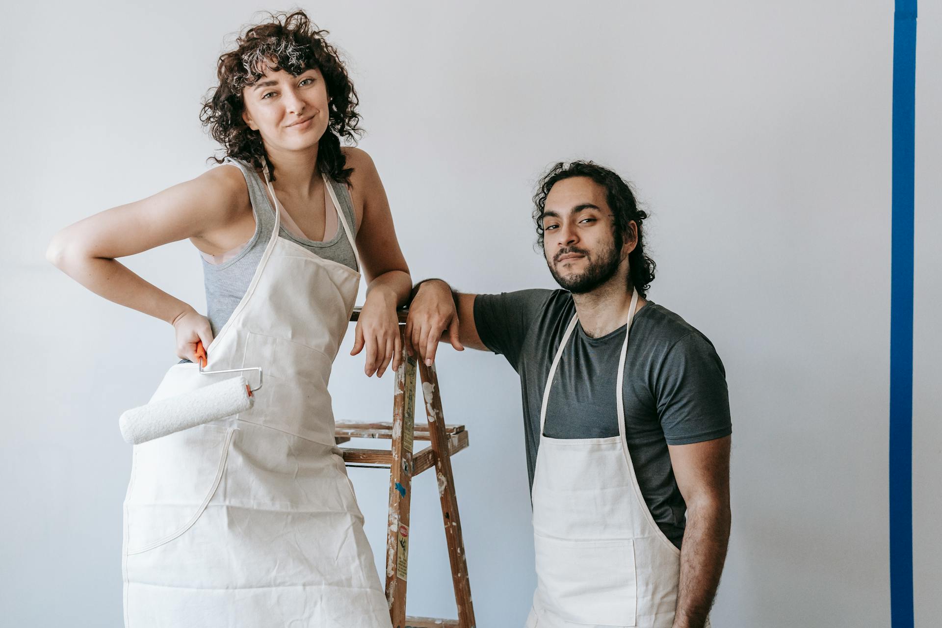 A couple painting their home's interior during a DIY renovation project.