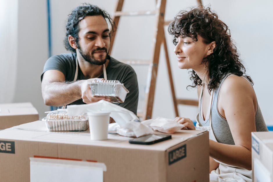 A couple relaxes with takeout food amidst moving boxes in their new home.