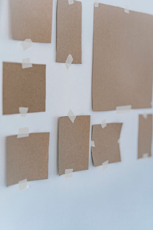 Free Minimalist display of cardboard sheets taped on a white wall, ideal for artistic and interior design inspirations. Stock Photo
