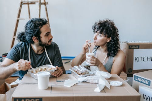 Ethnic couple interacting during lunch after moving in house