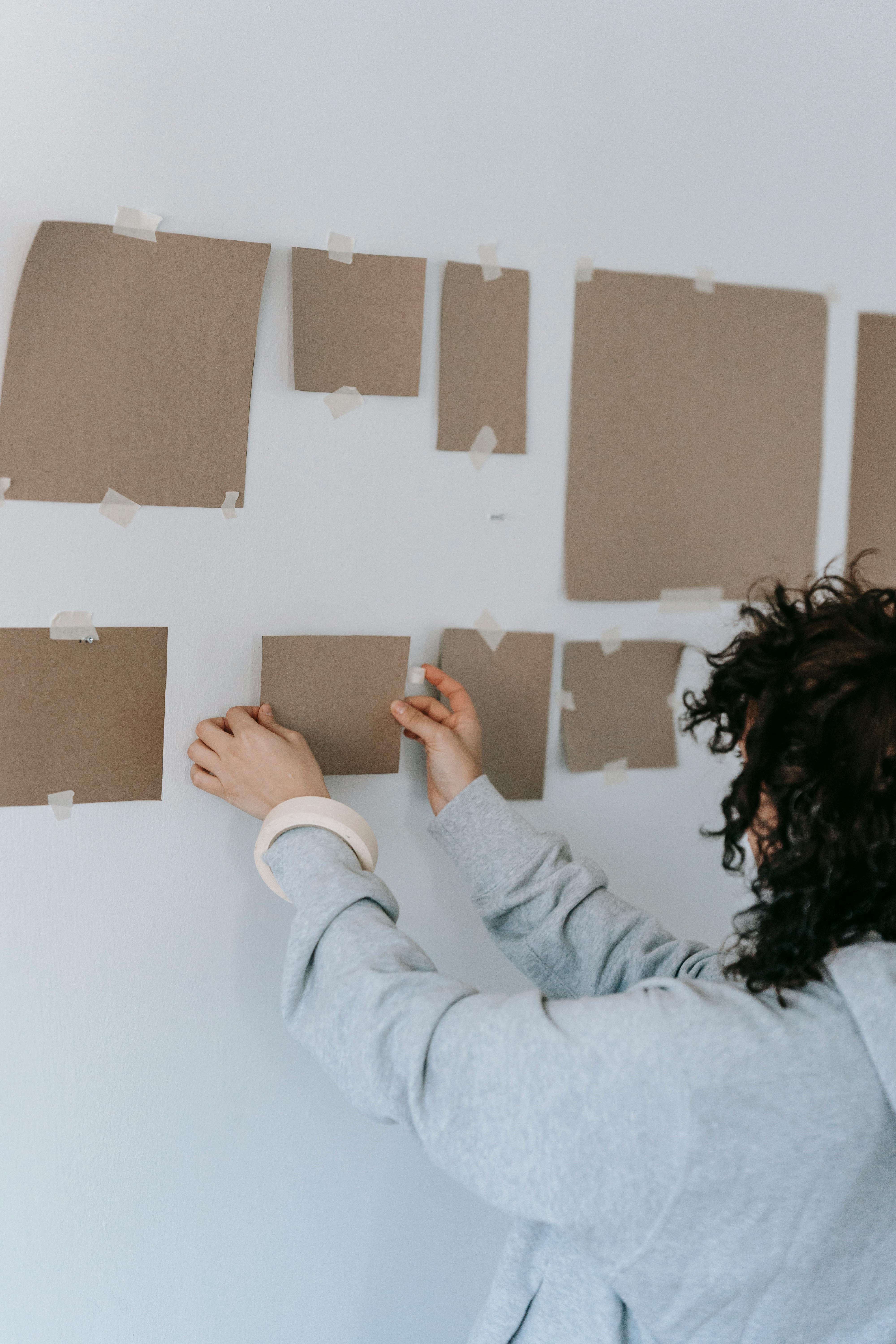 woman in gray long sleeve shirt holding brown cardboard on wall