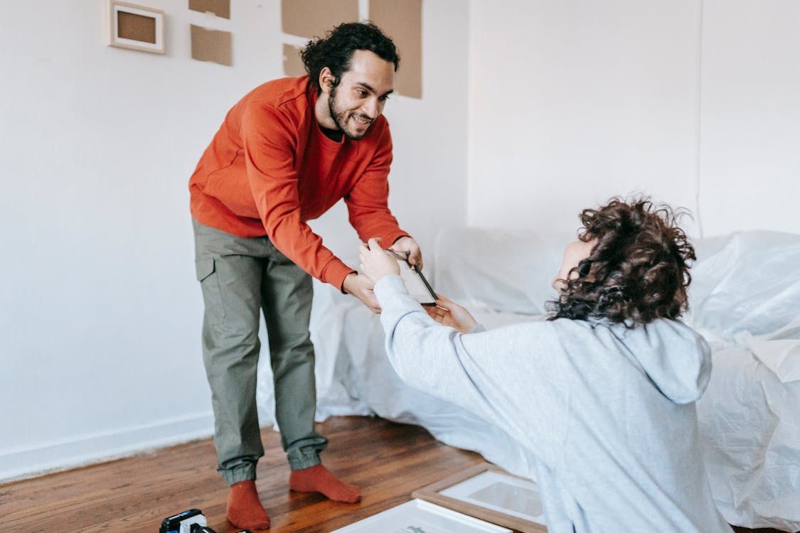 Couple Placing Picture Frames On Wall