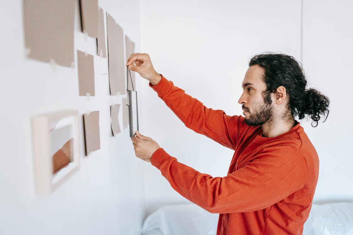 Man Putting Frame On Wall