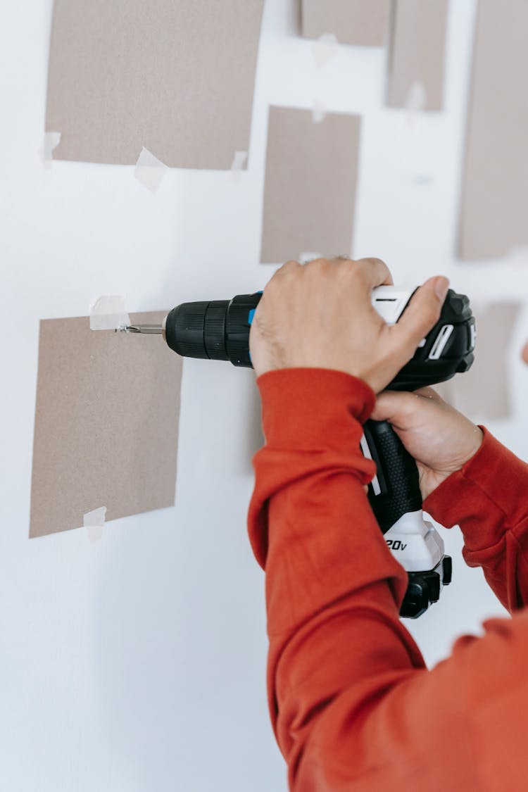 Person Drilling A Hole On Wall