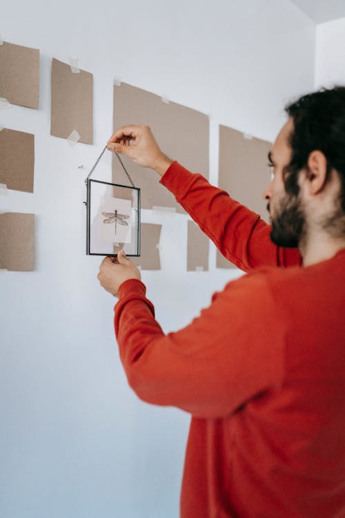 Man Hanging A Frame On Wall