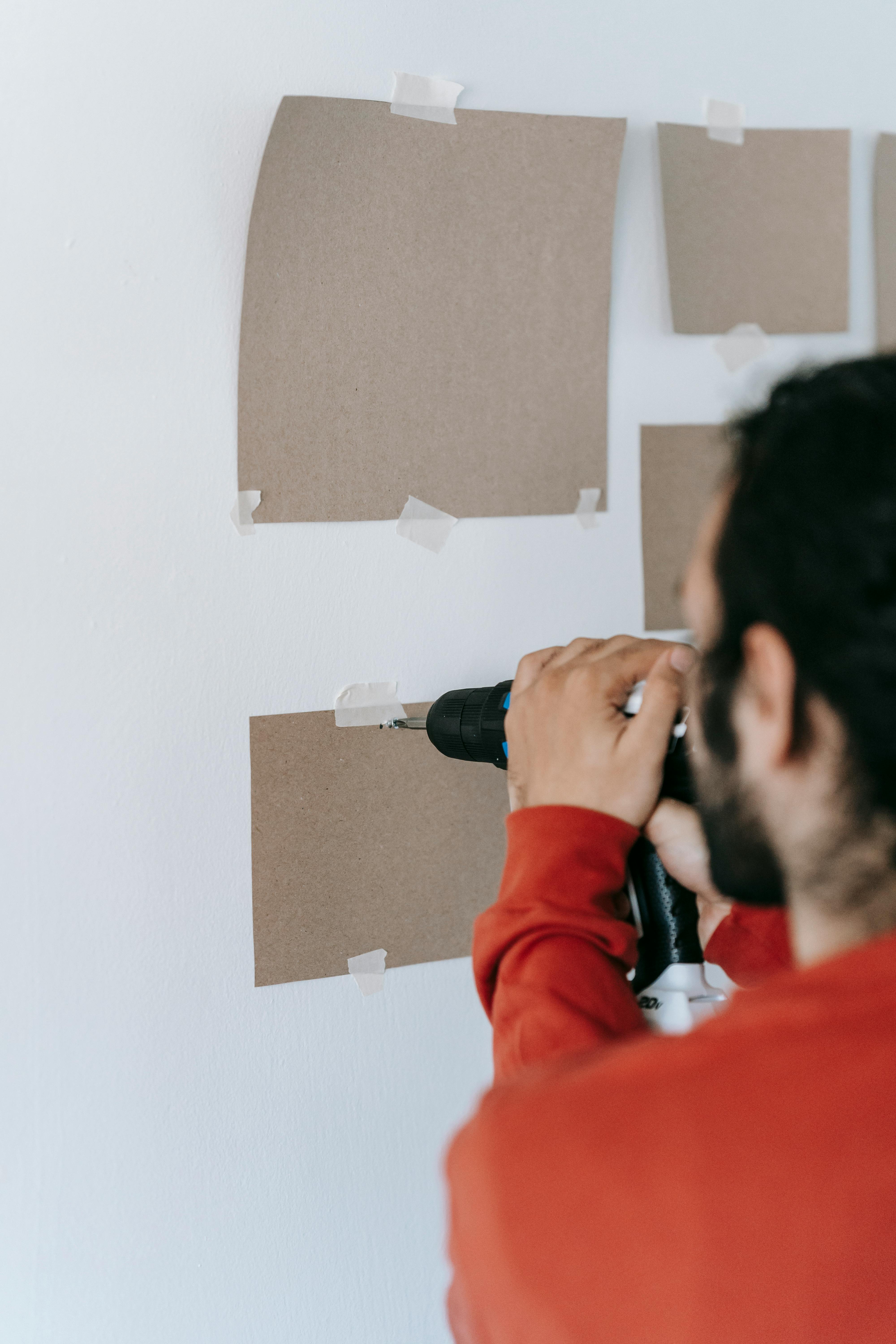 crop man inserting screw into wall with screwdriver at home