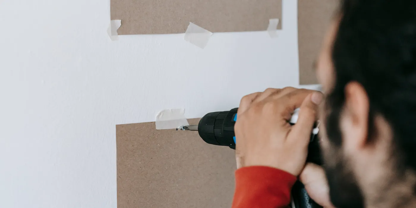 Technician drilling a wall mount for a display screen