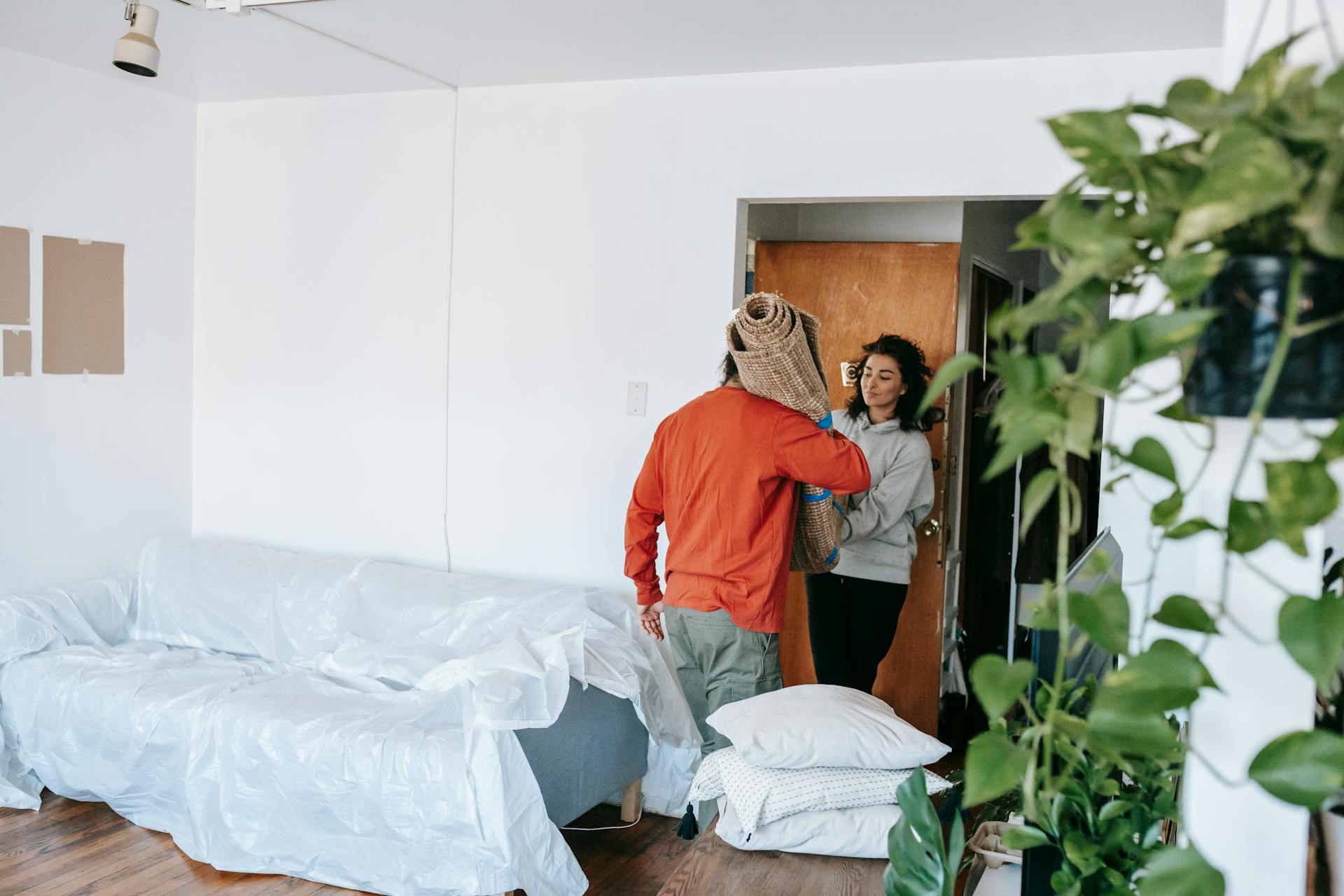 A couple arranging their new apartment, moving in furniture and household items.