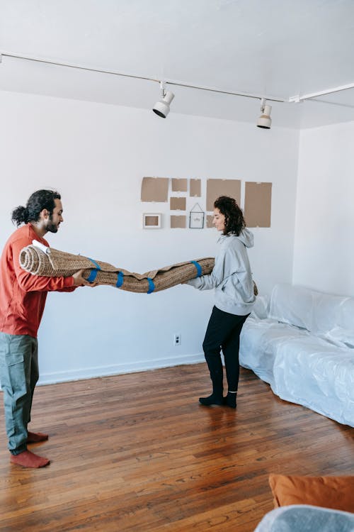 A Couple Carrying A Rolled Carpet