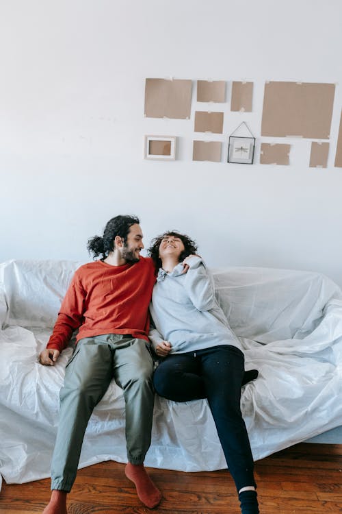 Man and Woman Sitting on White Couch