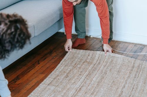 Free A couple arranging a carpet in a cozy living room, creating a warm home atmosphere. Stock Photo