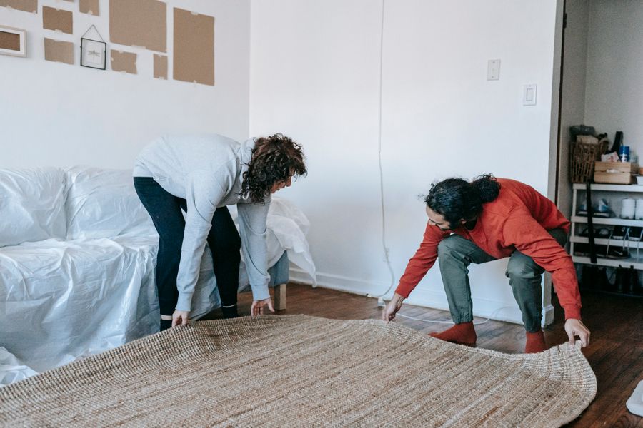 Fitters positioning a new carpet in a living room