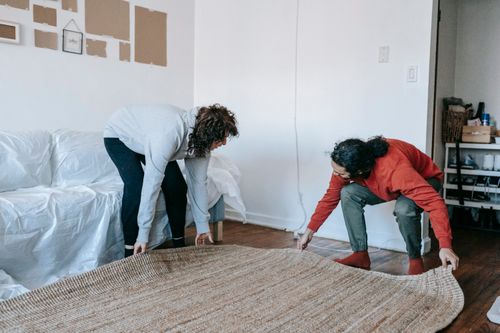 Free Couple arranging a rug in their contemporary apartment living room, teamwork concept. Stock Photo
