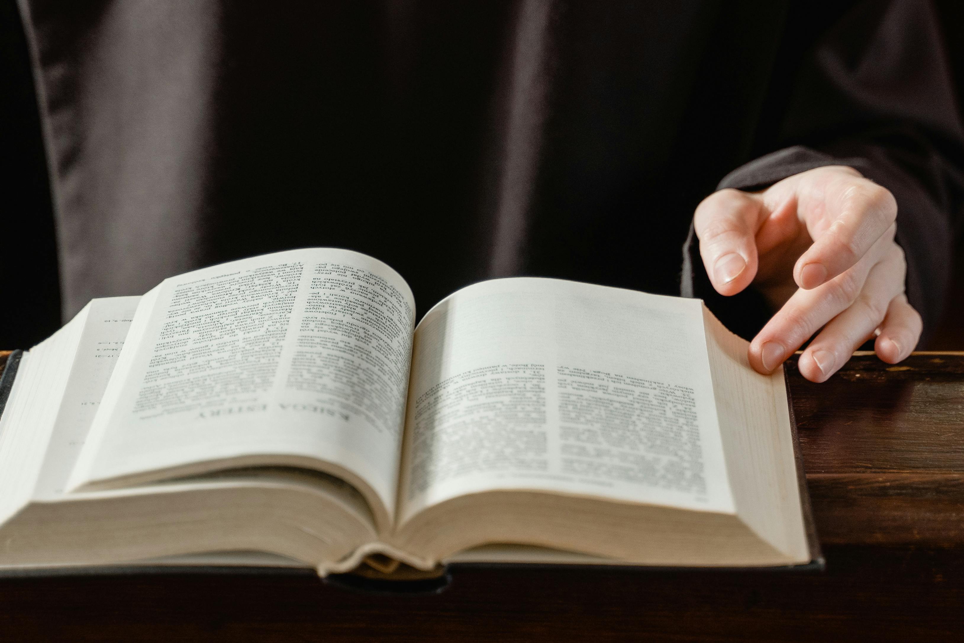 person reading book on brown wooden table