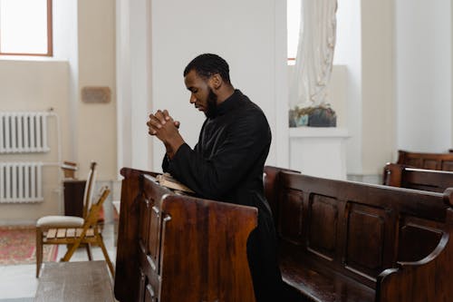 Man in Black Cassock Kneeling and Praying