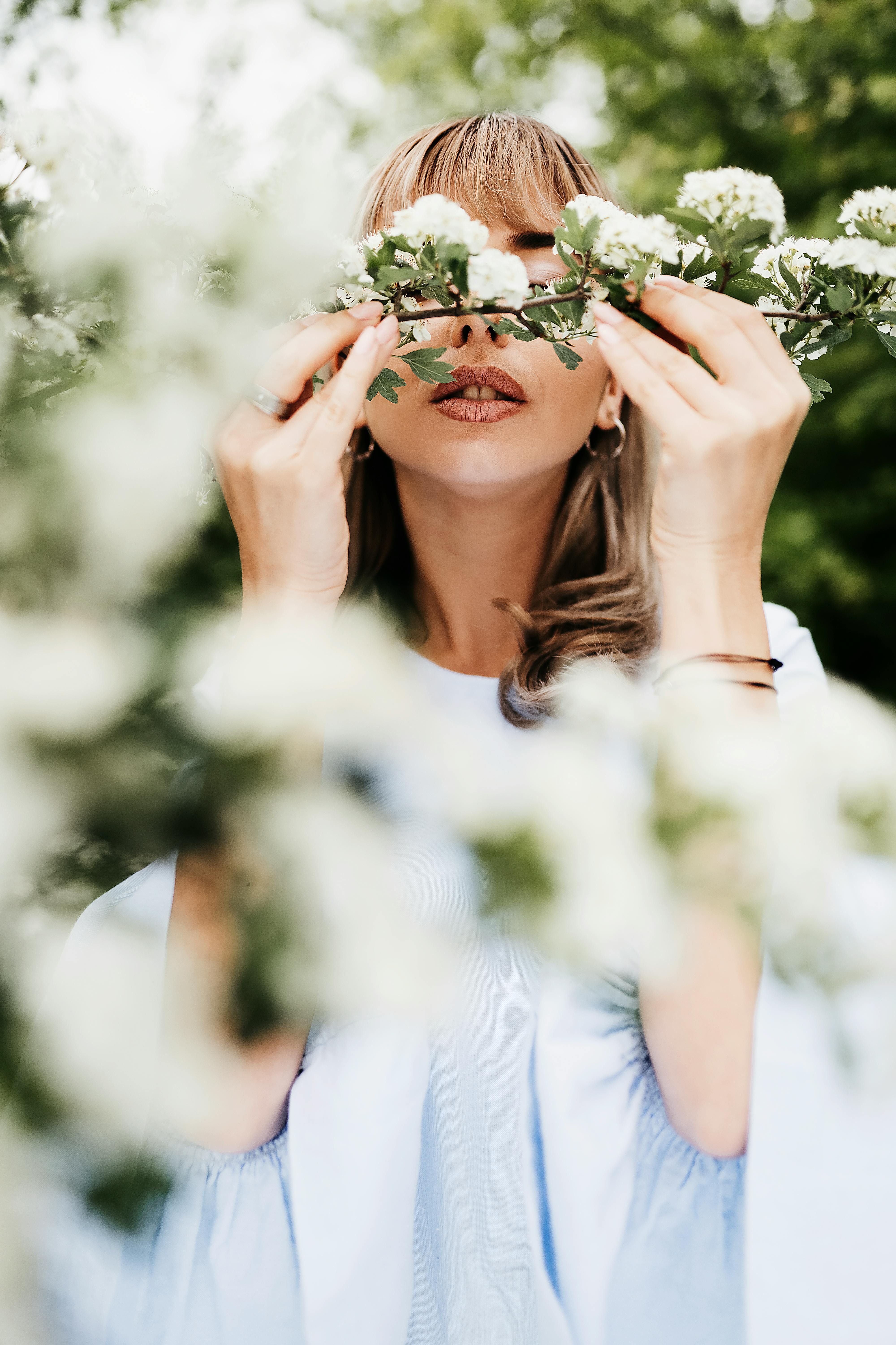 gentle woman smelling blooming flowers on shrub in garden