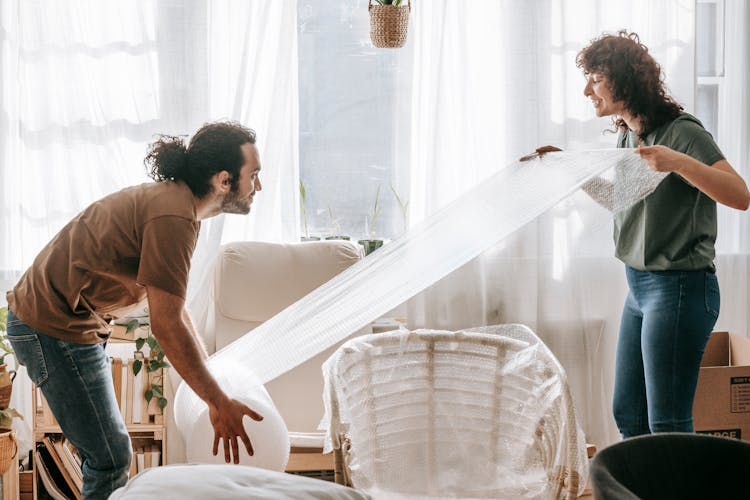 Couple Wrapping A Chair With Bubble Wrap