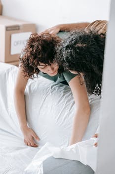 A young couple joyfully unpacks moving boxes in their new home, embracing relocation and togetherness.