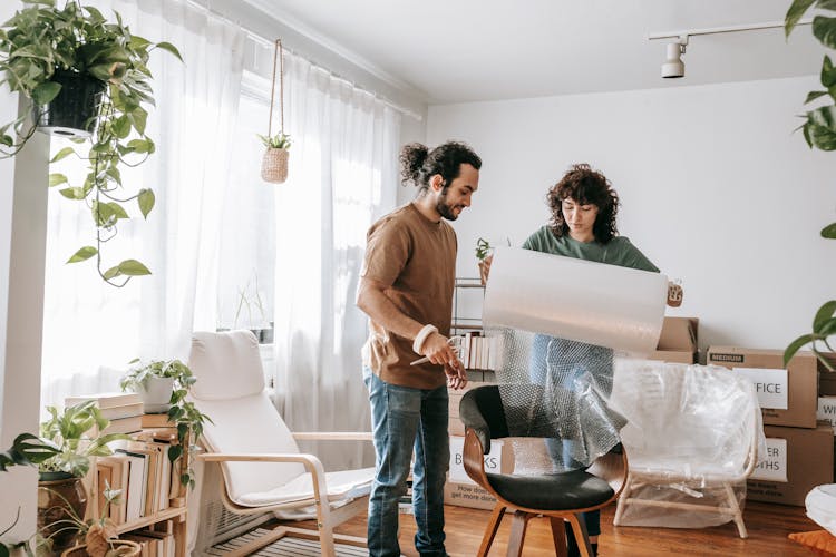 Couple Wrapping A Chair With Bubble Wrap