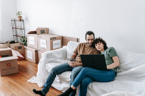 Couple Sitting On A Couch Browsing On Computer