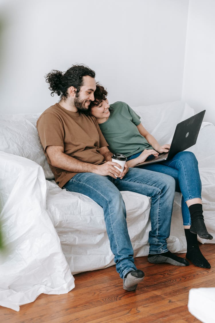 Couple Sitting On A Couch Using A Laptop