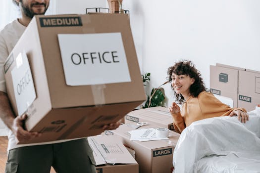Couple joyfully moving into their new apartment, surrounded by boxes labeled 'office.'