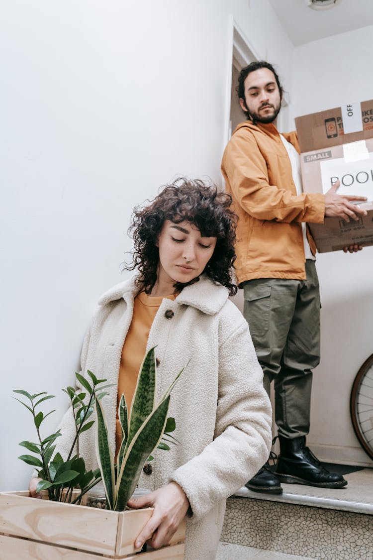 Woman Carrying Plants And Man With Boxes 