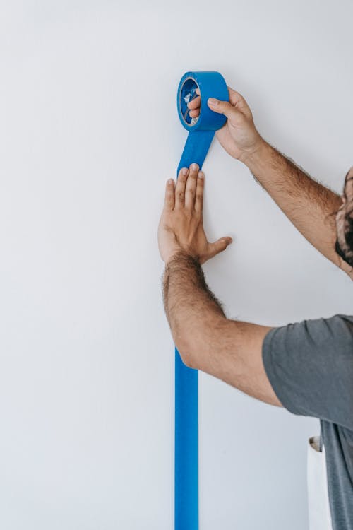 Crop Photo Of Man Putting Tape On Wall