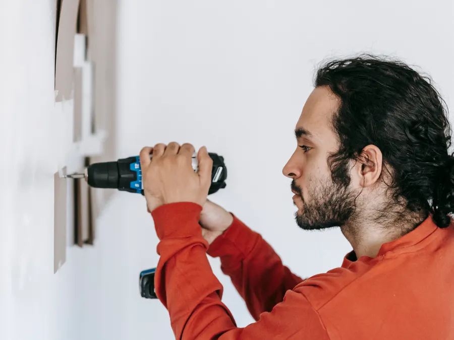 Installer drilling into a wall for display mounting