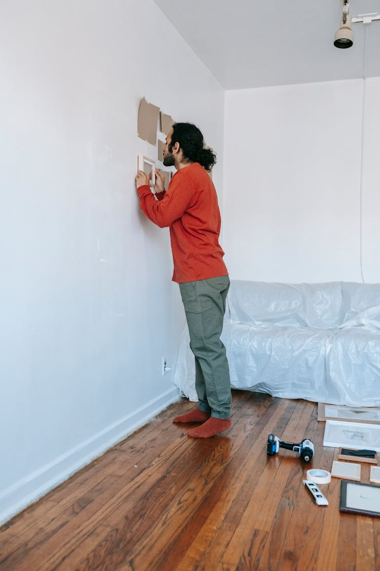 Man Hanging Picture Frames On Wall