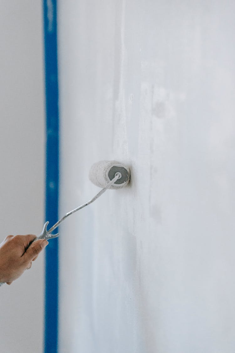 Person Painting The Wall With A Roller