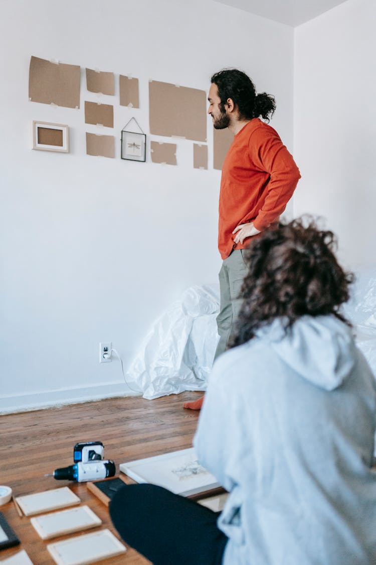 Man Hanging Picture Frames On Wall