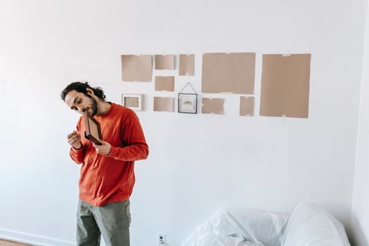 Man packing while moving out, holding a picture frame in a minimalist room.