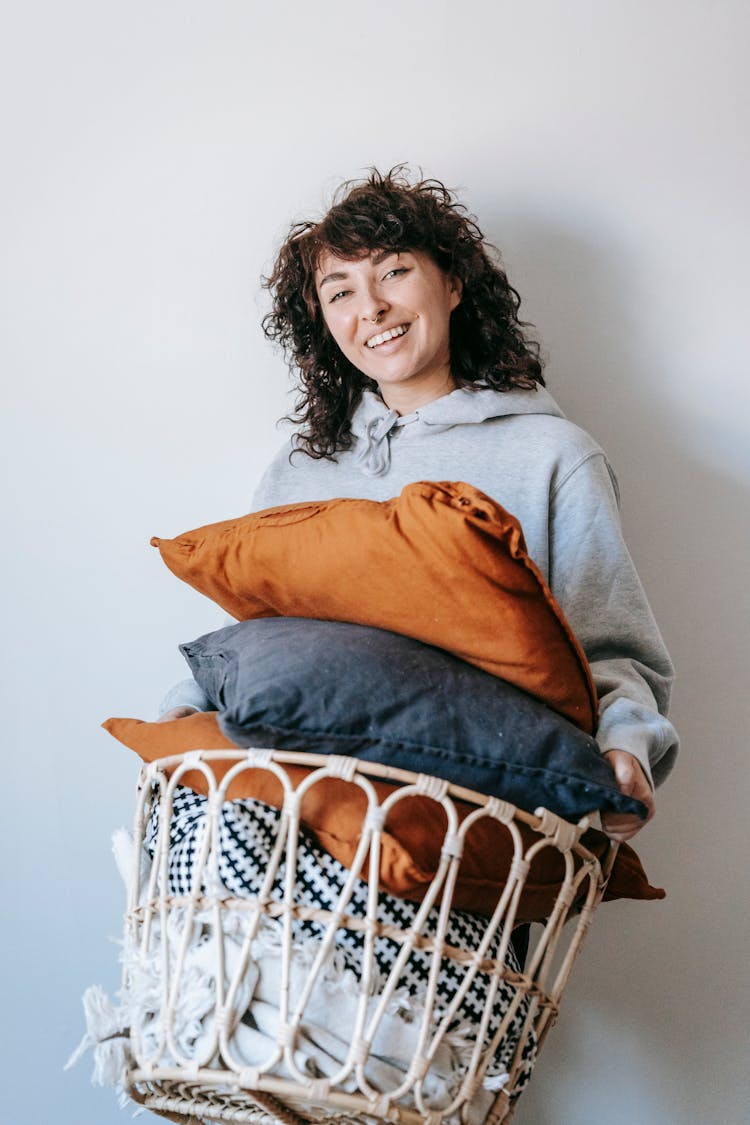 Woman In Gray Sweater Carrying A Basket Of Throw Pillows