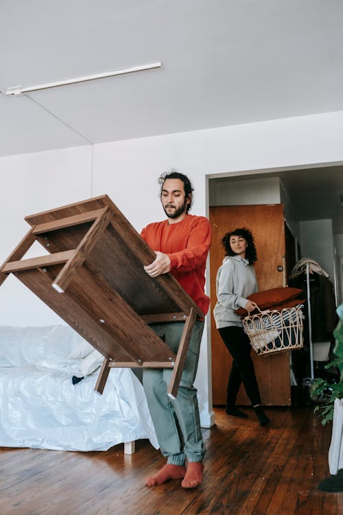 A Man Carrying A Wooden Table