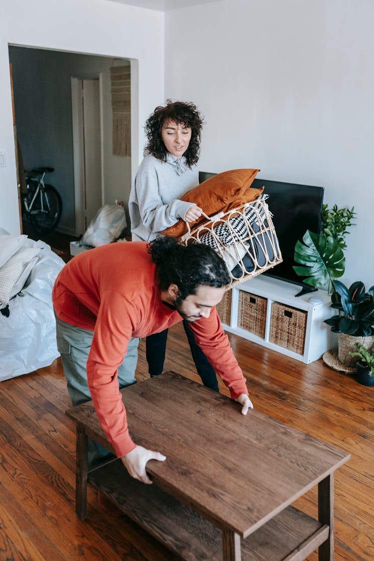 Woman Carrying A Basket Of Pillows And A Man Lifting A Table