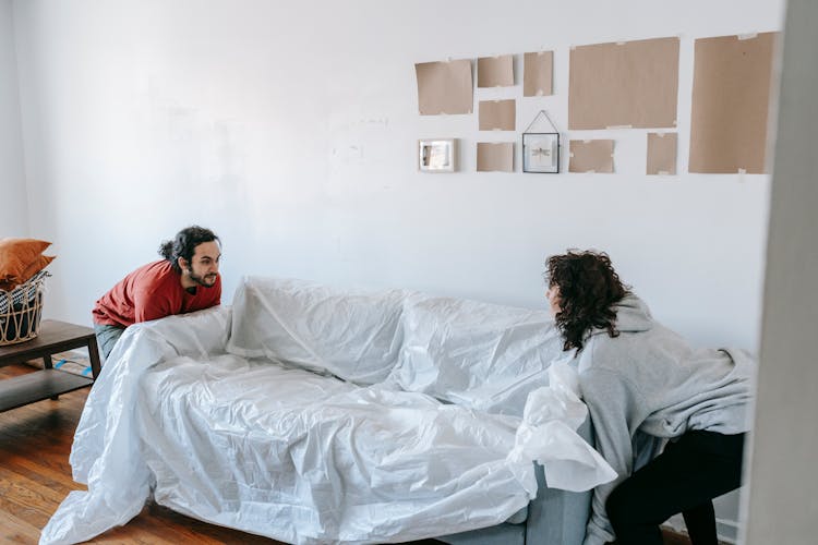 A Couple Lifting A Sofa